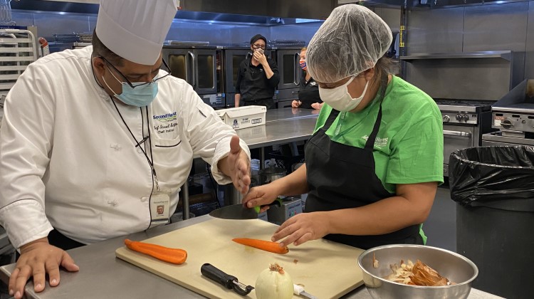 Chef instructor works with student in the Culinary Training Program during a knife skills lesson.
